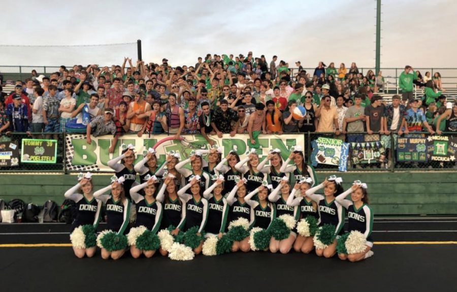 Notre Dame Cheerleaders with the Notre Dame student section at a football game.